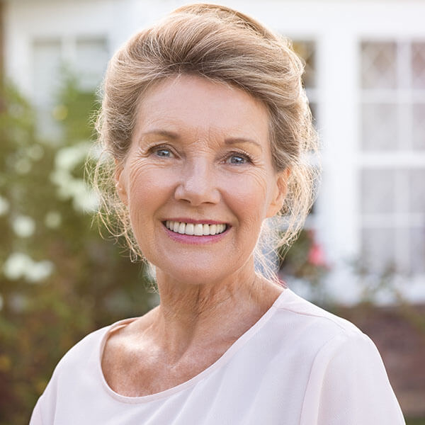 An older woman with dental implants smiling