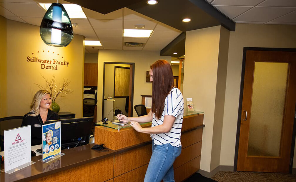 A female patient talking to team member at the front desk