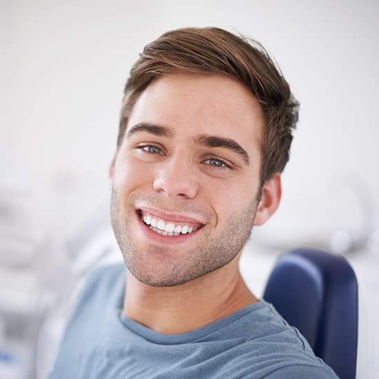 A man with white teeth sitting in a dental chair